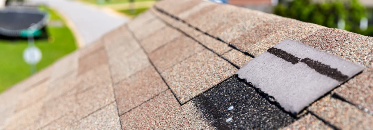 2 Close up shot of roof with lifted, damaged shingle.