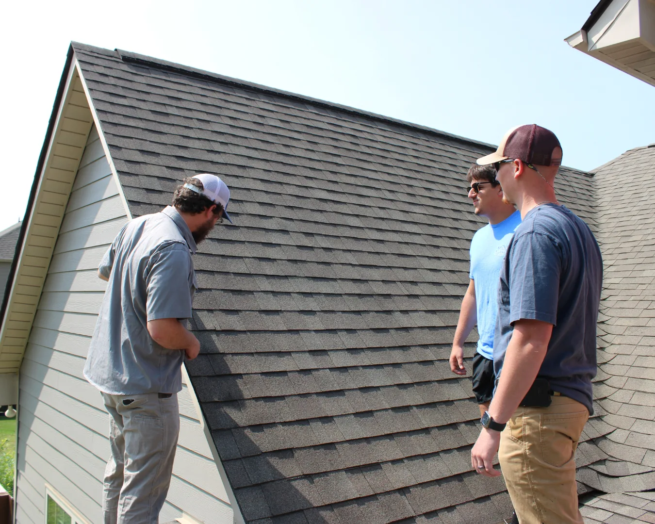 1 Team members from Turn Key roofing on top of residential roofing performing an inspection.