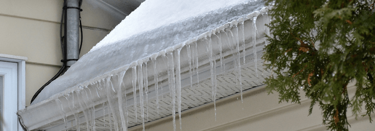 16 Close up of ice damns in gutters of roof with snow on it.