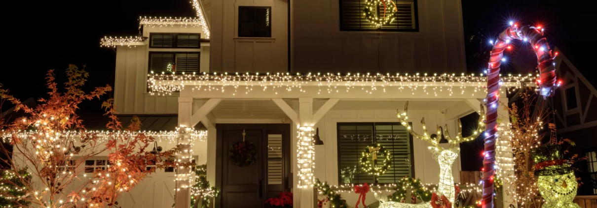 25 Front view of beautifully decorated two story home covered in lights and Christmas lawn decor.